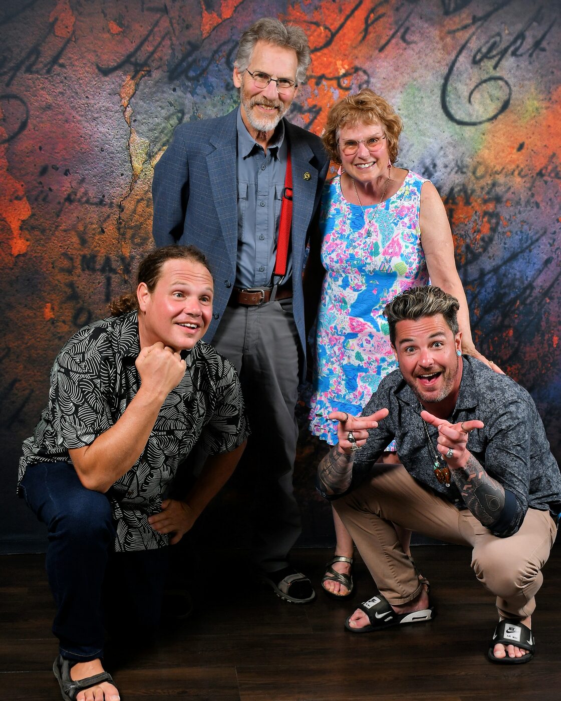 Group of four on a painted backdrop, two men kneeling in front