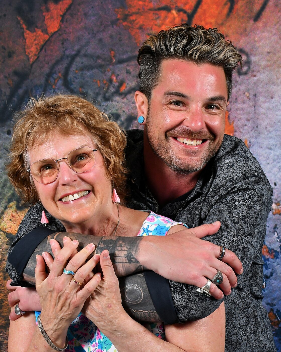 Woman laughing as a man hugs her from behind, painted studio backdrop