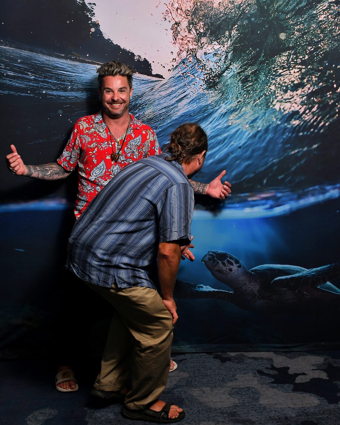 Two men playing in front of an ocean-wave backdrop
