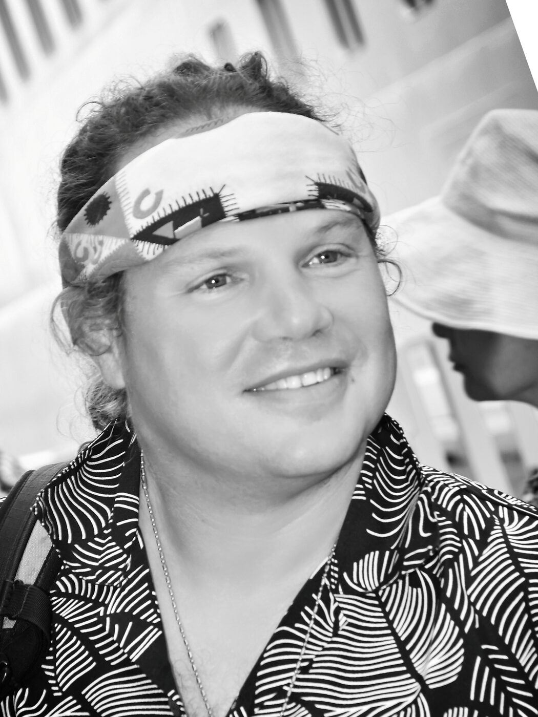 Black and white portrait of a smiling man in a bandana on deck