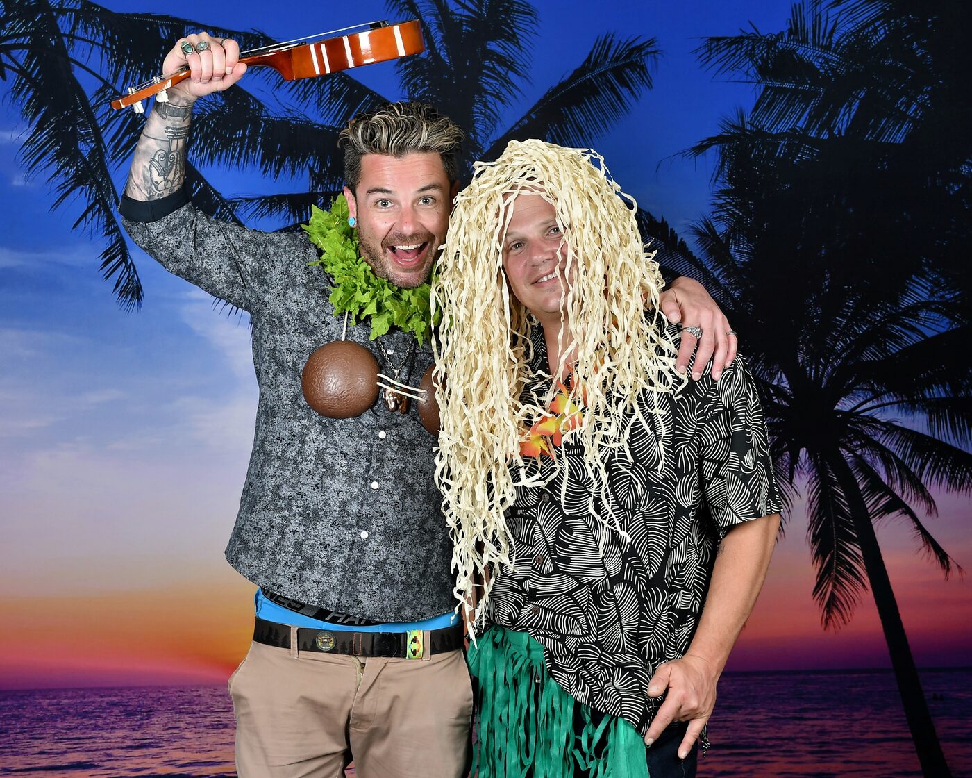 Man in a grass wig playing ukulele, sunset palm backdrop